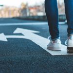 Henkilö kävelee asfaltilla, maahan maalattu nuolikuvio.,