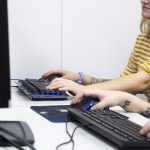 Kahden henkilön tatuoidut kädet näppäimistöillä